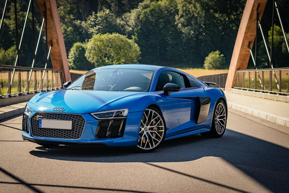A striking blue Audi R8 sports car parked on a bridge, highlighting luxury and design.